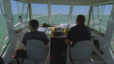 boat skippers in cabin of boat and pan to researchers in zodiac and dugong under the water swimming