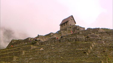 The terraced walls of Machu Picchu with a stone building on top.