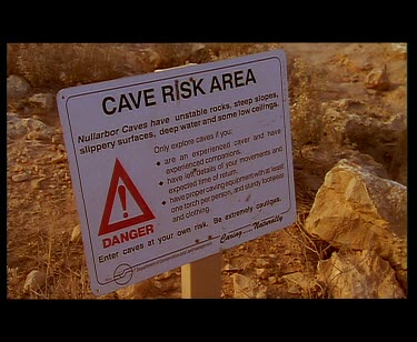 Danger warning sign for cave. People walking into cave