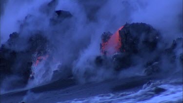 waves crashing directly over incandescent lava at the edge of lava delta volcano