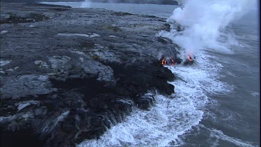 Where the edge of the Kilauea lava delta meets the ocean a line of steam rises into the air. Lava being washed out to sea.