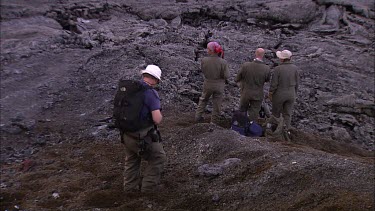 Scientists  and filmmakers walking over lava field