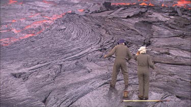 Scientists  throwing meters and measuring equipment into lava flow