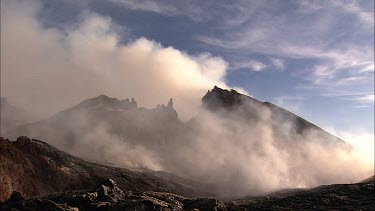 Volcano summit caldera. Steam and smoke. Sunset.  Eerie lunar apolcalyptic landscape.