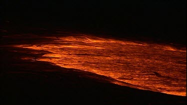 Incandescent lava erupting out of a fissure. Night.  Flowing in a lava channel