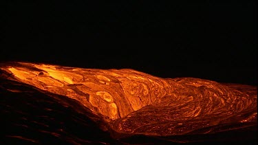 The molten rock incandescent lava moving across the surface. It looks plastic in form, soft and maleable as if it is being extruded. Bubbling out of the earth.