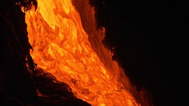 A river of incandescent lava flowing down a lava channel. Night