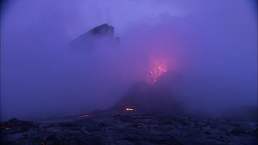 Lava sputtering and erupting out of a vent. Volcanic eruption. Night