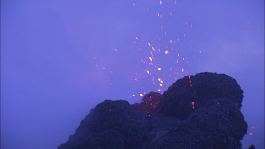 Lava sputtering and erupting out of a vent. Volcanic eruption. Smokey eerie landscape