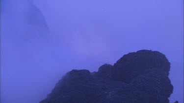 Lava sputtering and erupting out of a vent. Volcanic eruption. Smokey eerie landscape