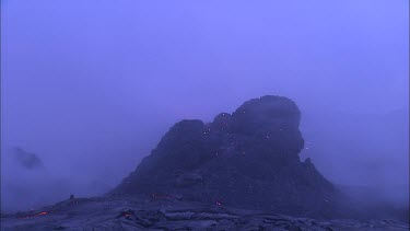Lava sputtering and erupting out of a vent. Volcanic eruption. Smokey eerie landscape