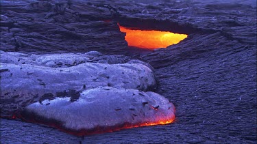 Incandescent lava seeping slowly and cooling. The top of the lava flow has already cooled to black