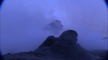 Lava sputtering and erupting out of a vent. Volcanic eruption. Smokey eerie landscape