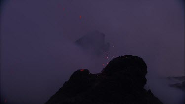 Lava sputtering and erupting out of a vent. Volcanic eruption. Smokey eerie landscape