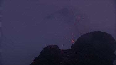 Lava sputtering and erupting out of a vent. Volcanic eruption. Smokey eerie landscape