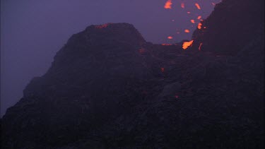 Lava sputtering and erupting out of a vent. Volcanic eruption. Smokey eerie landscape